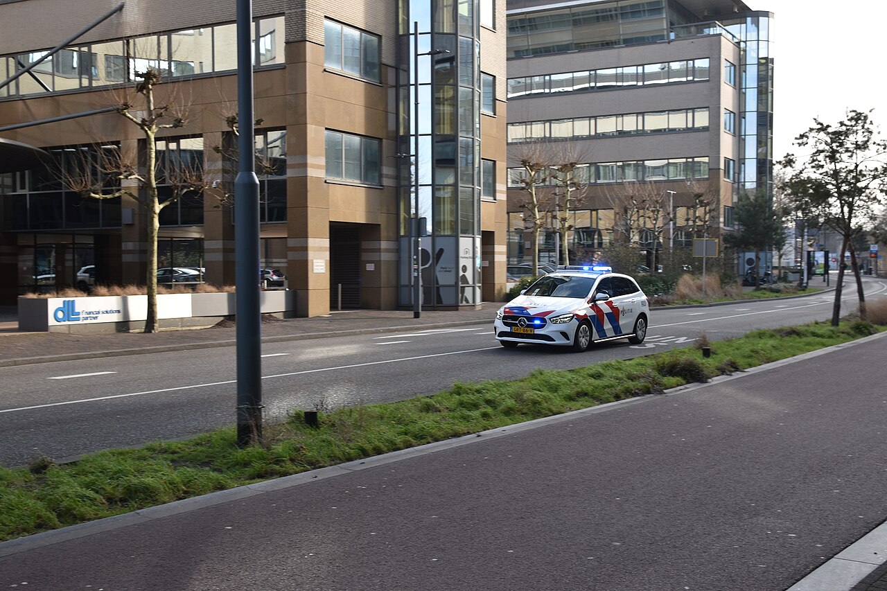 Politieauto met zwaailichten rijdend over de Vestdijk in Eindhoven